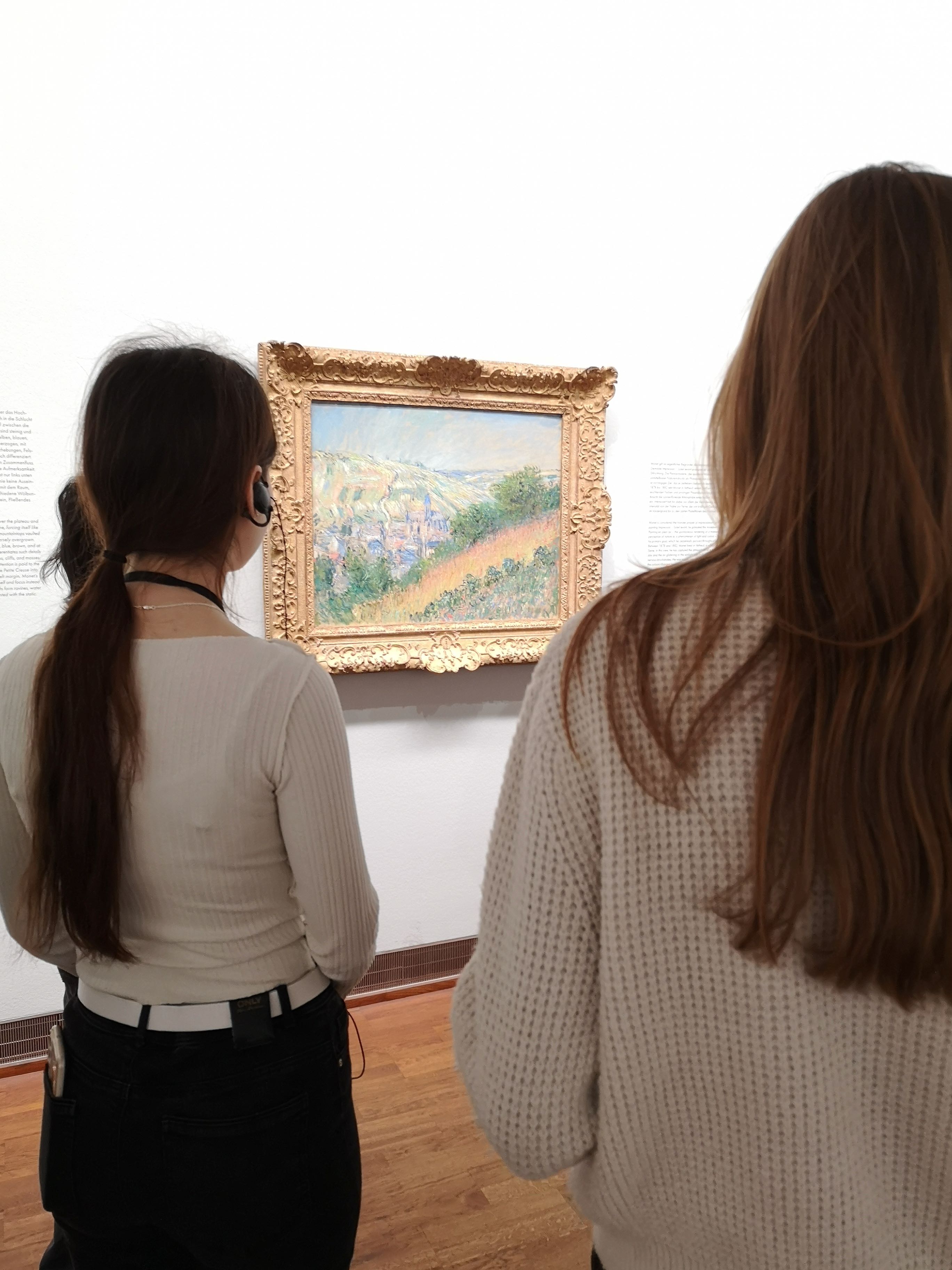 SchuelerInnen betrachten ein impressionistisches Gemaelde von Claude Monet.